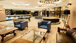 A modern lobby with seating areas, a bar, and a large chandelier.