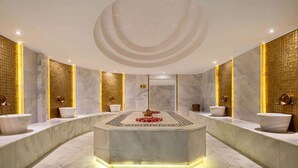 A luxurious bathroom with marble countertops, gold accents, and a central decorative piece.