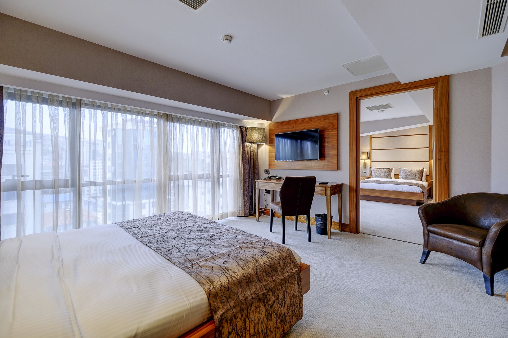 Una habitación de hotel con una cama grande, un escritorio, un televisor y una silla.