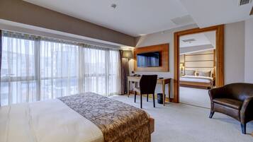 Una habitación de hotel con una cama grande, un escritorio, un televisor y una silla.