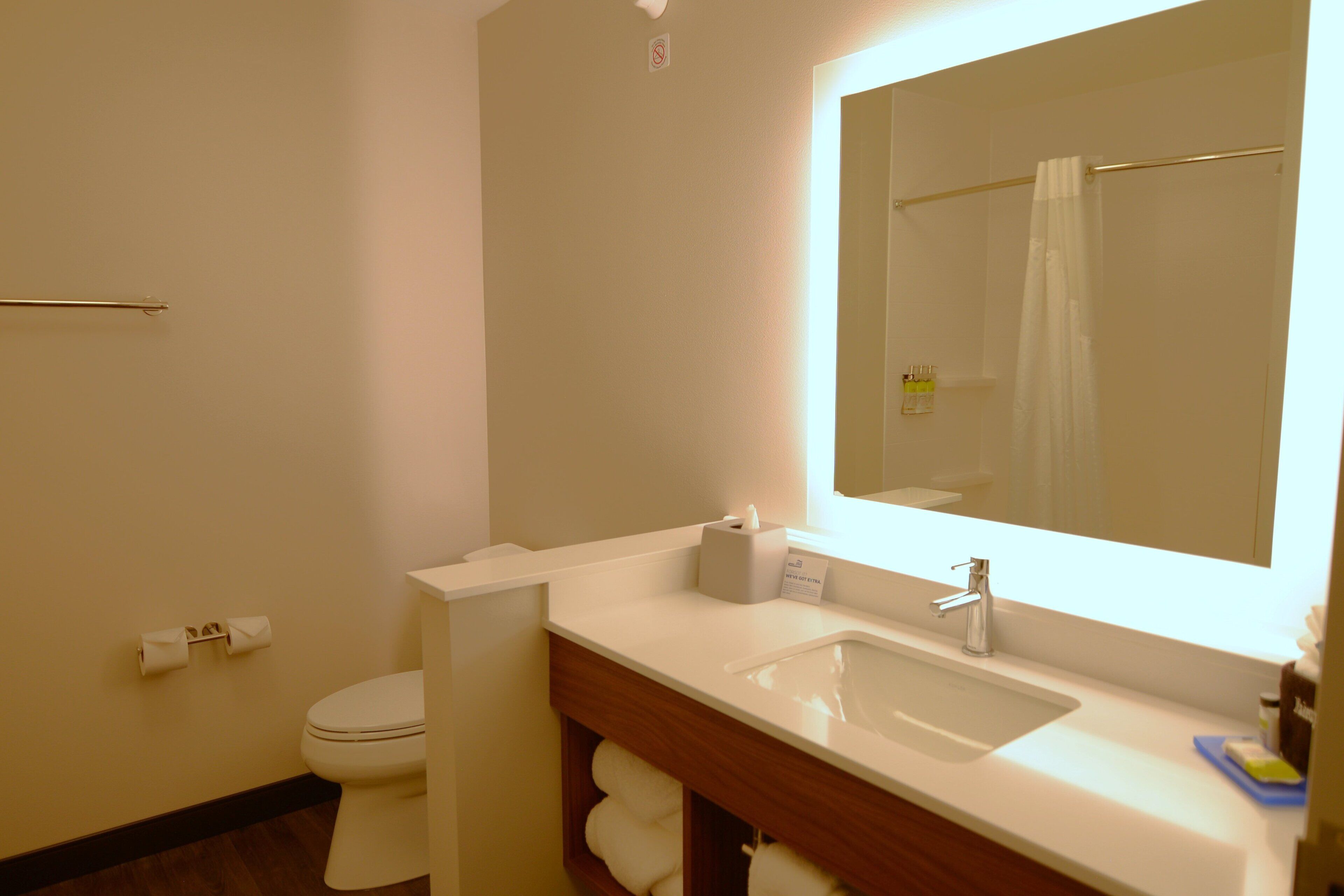 Un baño con inodoro, lavabo, espejo y toallero.