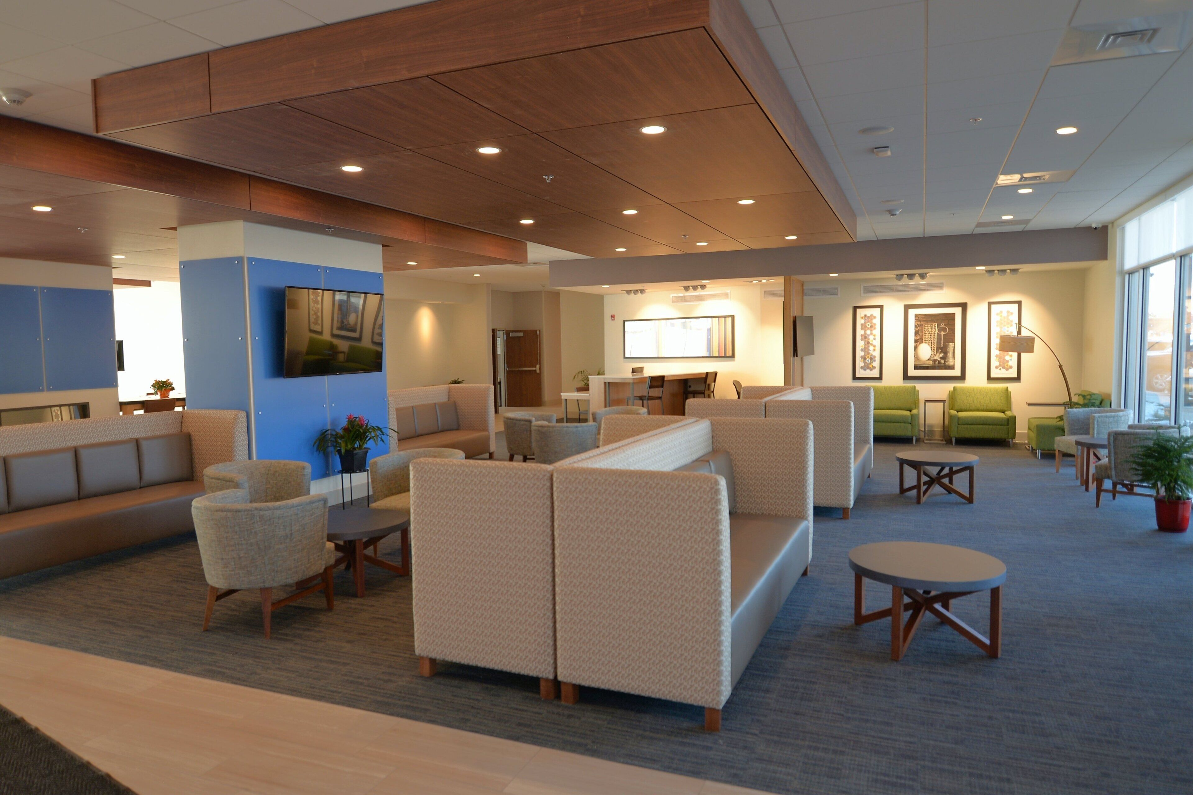 A modern lobby with sofas, chairs, a TV, and artwork on the walls.
