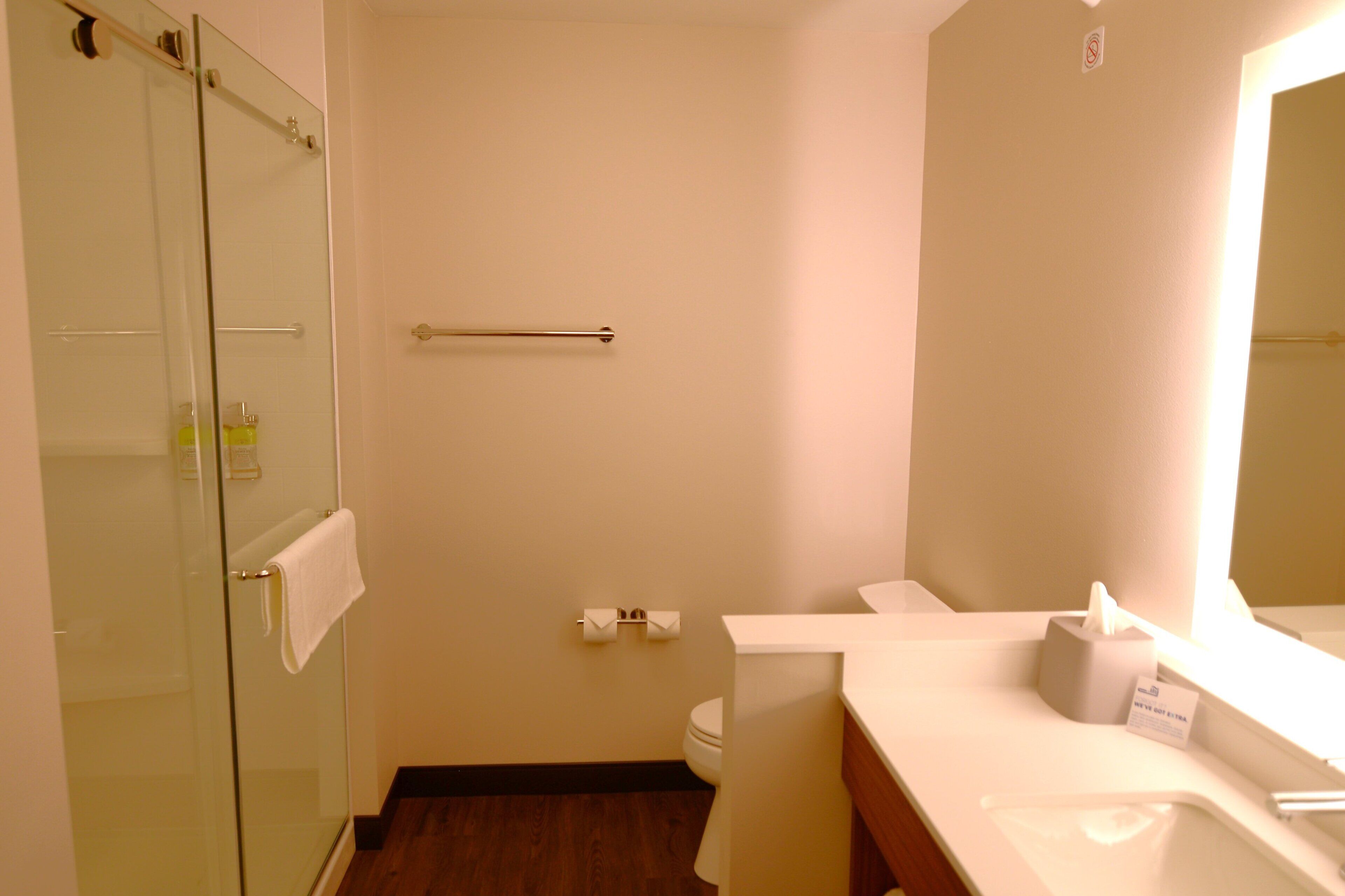 Un baño con cabina de ducha de vidrio, inodoro blanco y lavabo con espejo.