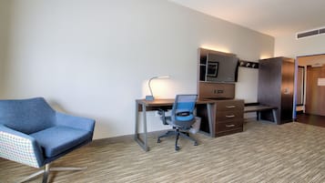 A hotel room with a desk, chair, and wardrobe.