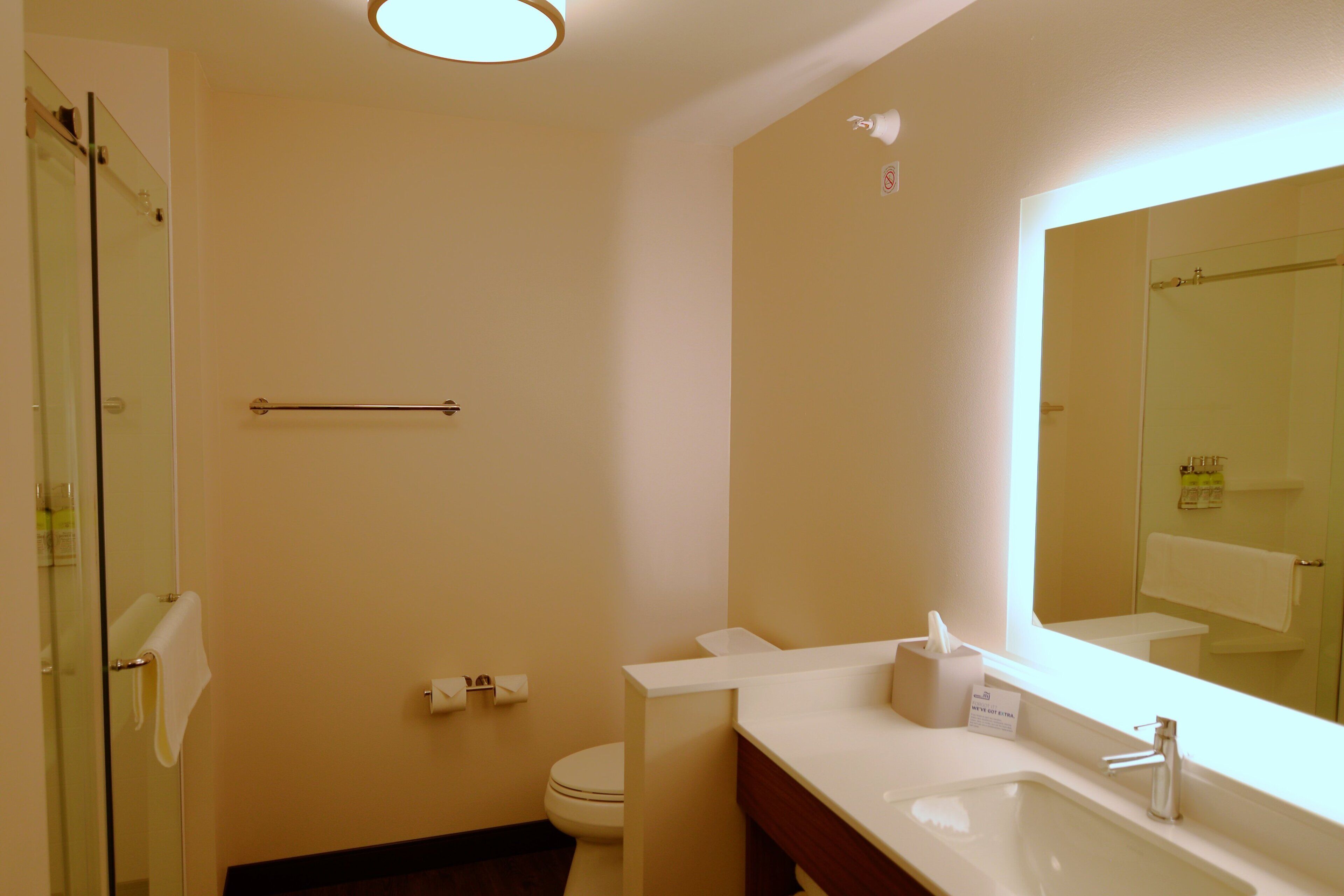 Une salle de bain avec une douche à parois de verre, des toilettes, un lavabo avec un miroir et un porte-serviettes.