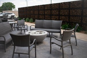An outdoor seating area with wicker furniture and a central fire pit.