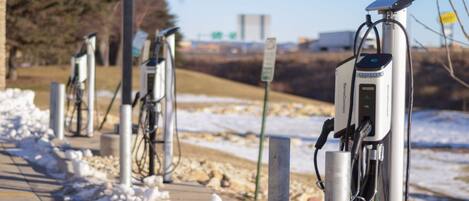 A row of electric vehicle charging stations along a paved path with snow on the ground.