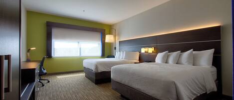 Quarto de hotel com duas camas, uma mesa e uma janela.