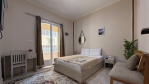 A bedroom with a bed, a desk, a chair, a bedside table, a mirror, and a potted plant. - Downtown Cairo Sweet Home (Cairo)