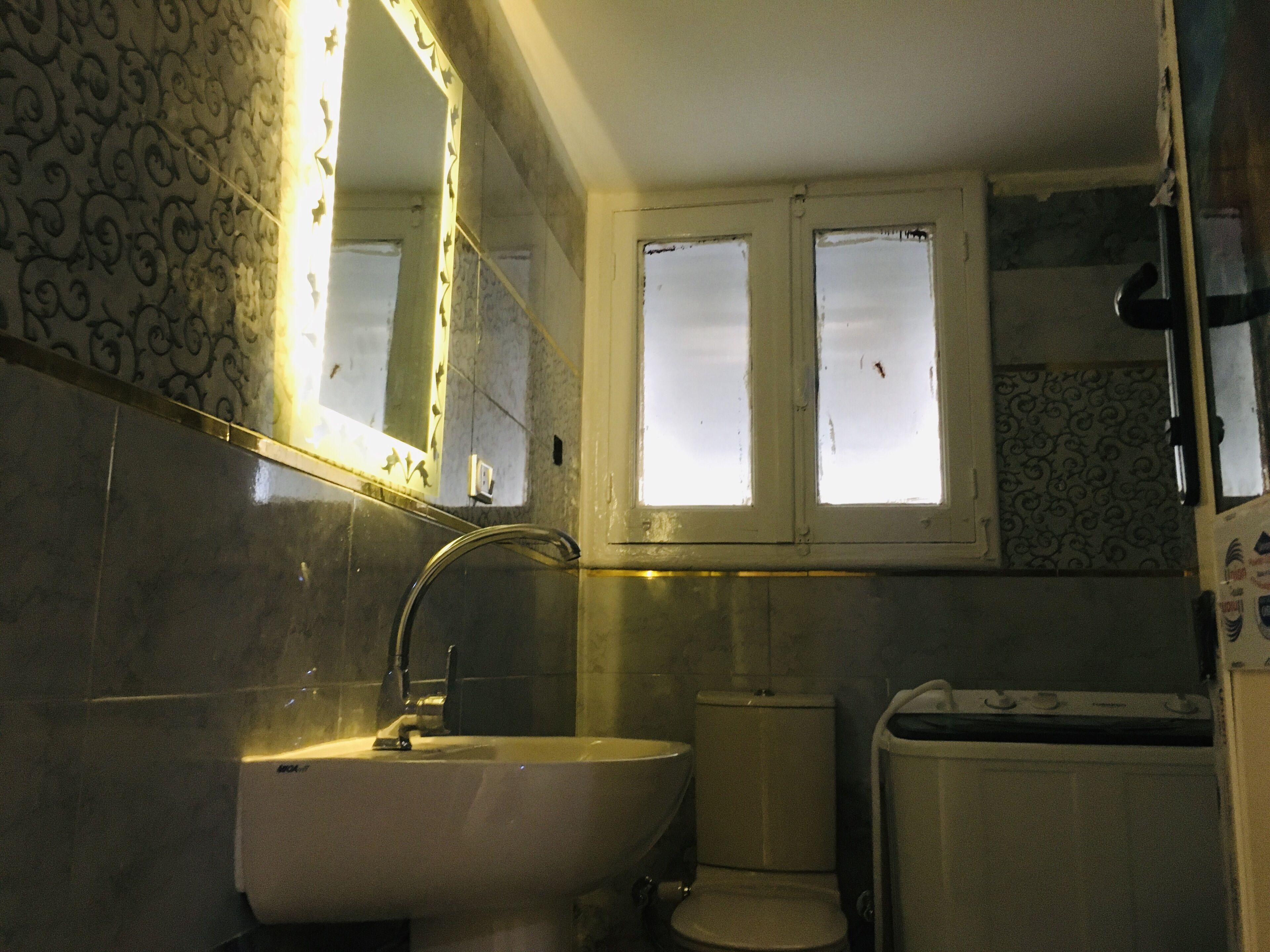 A bathroom with a sink, toilet, and bathtub. There is a window above the toilet and a mirror above the sink.