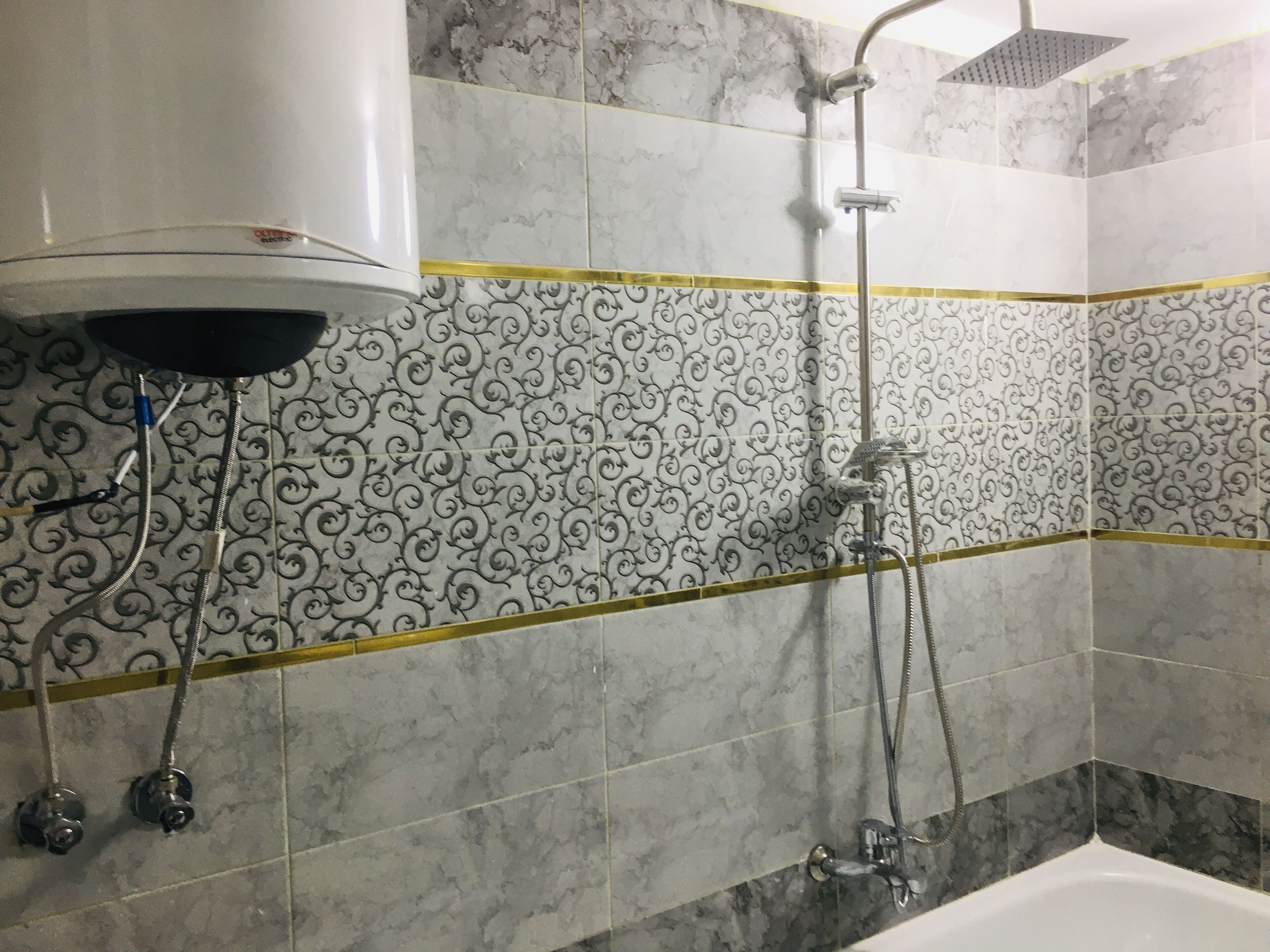 Ein Badezimmer mit Dusche, Toilette und Waschbecken. Die Wände sind mit einem Marmormuster und einem gelben Streifen versehen.