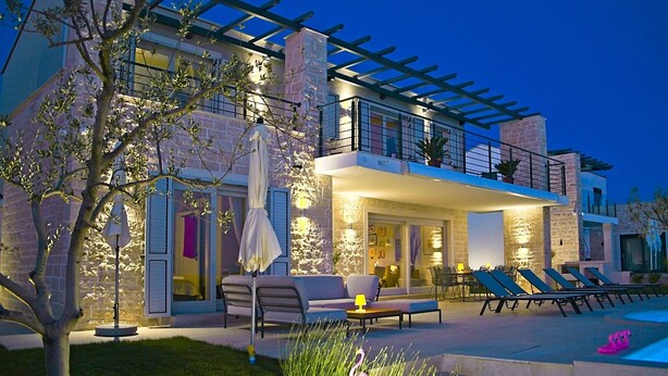 Une maison moderne dotée d’un balcon, d’un espace salon extérieur et d’une piscine.