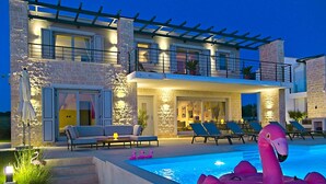 Une maison moderne à deux étages dotée d’une piscine, d’un espace salon extérieur et d’un flotteur en forme de flamant rose.
