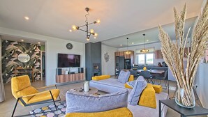 Un salon moderne avec un canapé, des fauteuils, une table basse et un téléviseur.