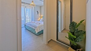 Une chambre d’hôtel avec un grand lit, un miroir, une plante en pot et une vue sur l’extérieur.