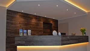 A reception desk with a wooden panel backdrop, a white counter, and recessed lighting.