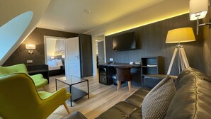 A modern hotel room with a living area, a dining space, and a bedroom.