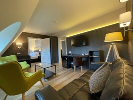 Ein modernes Hotelzimmer mit Wohnbereich, Essbereich und Schlafzimmer.