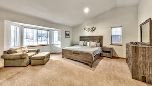 Quarto com cama grande, sofá, cômoda e mesa de cabeceira.