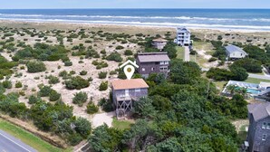 Una proprietà costiera con diversi edifici, una spiaggia e vegetazione lussureggiante.
