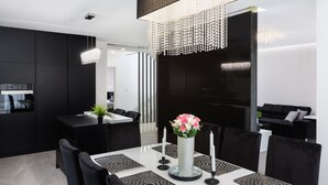 A modern kitchen with black cabinetry, a dining area with a white table and black chairs, and a chandelier. - VILLA ELLA - Pool villa for 8 persons near Medulin (Medulin)