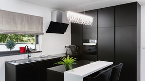 A modern kitchen with a central island, black cabinetry, a flat-screen TV, and a chandelier. - VILLA ELLA - Pool villa for 8 persons near Medulin (Medulin)