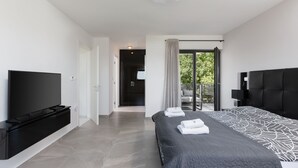 A modern bedroom with a large bed, a flat-screen TV, and a balcony with a view of greenery. - VILLA ELLA - Pool villa for 8 persons near Medulin (Medulin)
