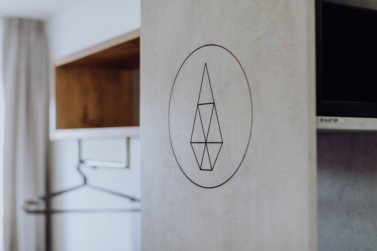 Un logotipo geométrico en una pared, una estantería de madera y un televisor.