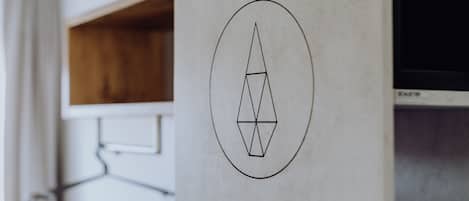 A geometric logo on a wall, a wooden shelf, and a television.