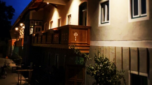 Un edificio tradicional con un balcón y un cartel con un símbolo.