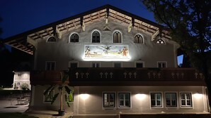 Un edificio con un gran mural iluminado en la fachada, varias ventanas y un área de entrada bien iluminada.