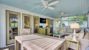 A covered outdoor patio with a wooden table, wicker chairs, a sofa, and a ceiling fan. - Award-Winning Resort Amenities | Sandpiper Court 14 (Isle of Palms)