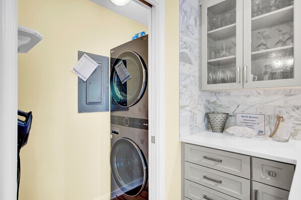Un área de lavandería con dos lavadoras, un mueble con puertas de vidrio y un cartel de acceso a Wi-Fi.