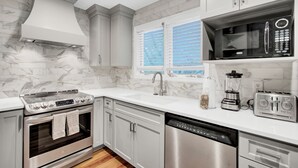 A modern kitchen with a built-in oven, stainless steel dishwasher, and a microwave. - Award-Winning Resort Amenities | Sandpiper Court 14 (Isle of Palms)