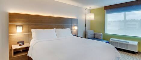 Habitación de hotel con una cama grande, mesitas de noche, una lámpara de pared, ventana con vistas y calefacción integrada.