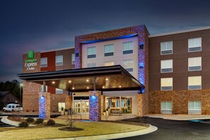 A Holiday Inn Express building with a brick facade, a covered entrance, and a well-lit exterior.