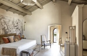 A spacious bedroom with a large bed, a chair, and a desk. There is a window with a view of the outside. - Palazzo Maresgallo (Lecce)