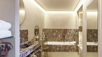 A modern bathroom with a marble vanity, a freestanding bathtub, and a large mirror.