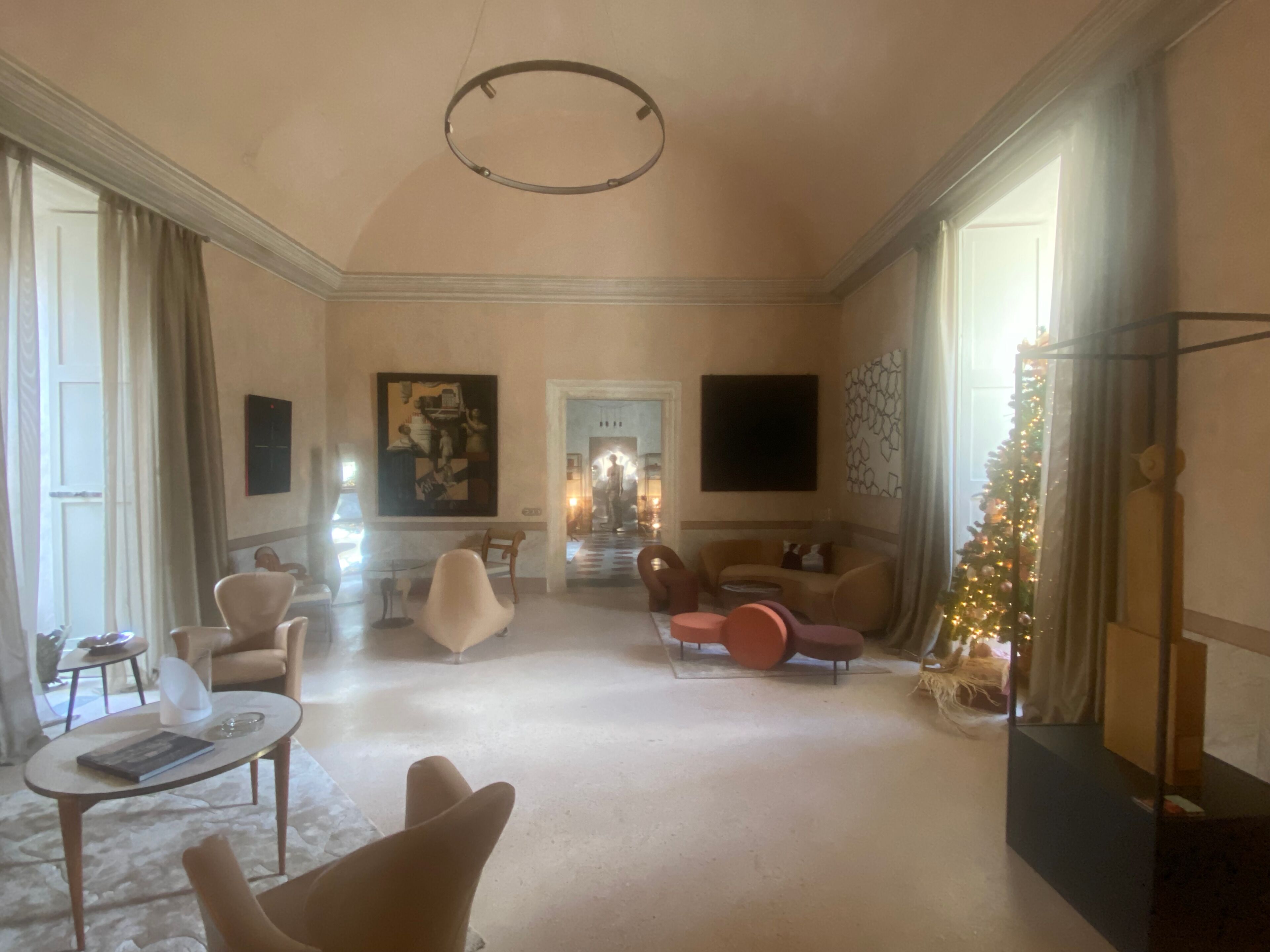 Ein geräumiges Wohnzimmer mit hoher Decke, einem großen Gemälde an der Wand und einem Weihnachtsbaum.