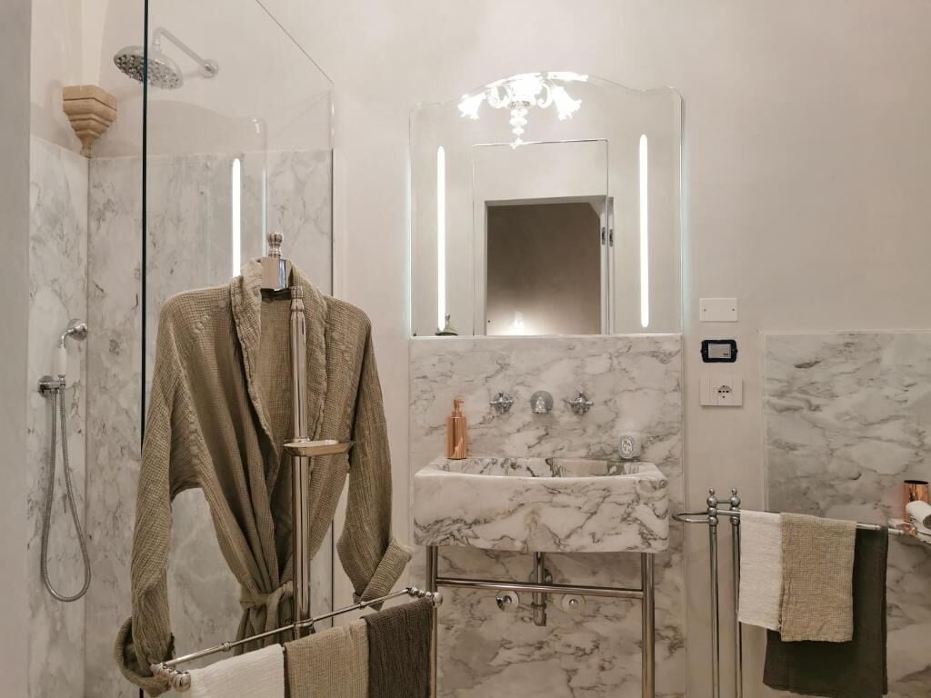 A modern bathroom with a glass-enclosed shower, a marble sink, and a large mirror.