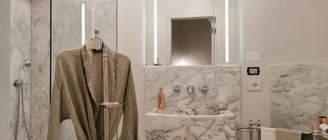 A modern bathroom with a glass-enclosed shower, a marble sink, and a large mirror.