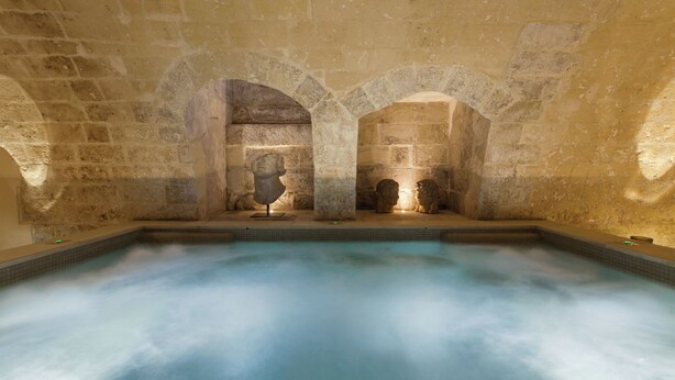 A stone-walled spa with a central pool and three arched niches containing statues. - Palazzo Maresgallo (Lecce)
