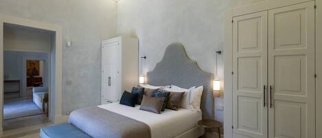A bedroom with a large bed, bedside tables, a wardrobe, and a bench.