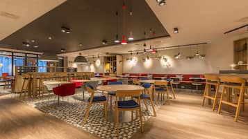 A modern dining area with round tables, wooden chairs, and pendant lighting.