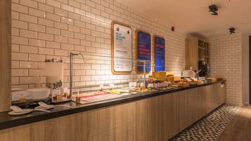 A hotel reception area with a long counter, a coffee machine, and a breakfast bar.