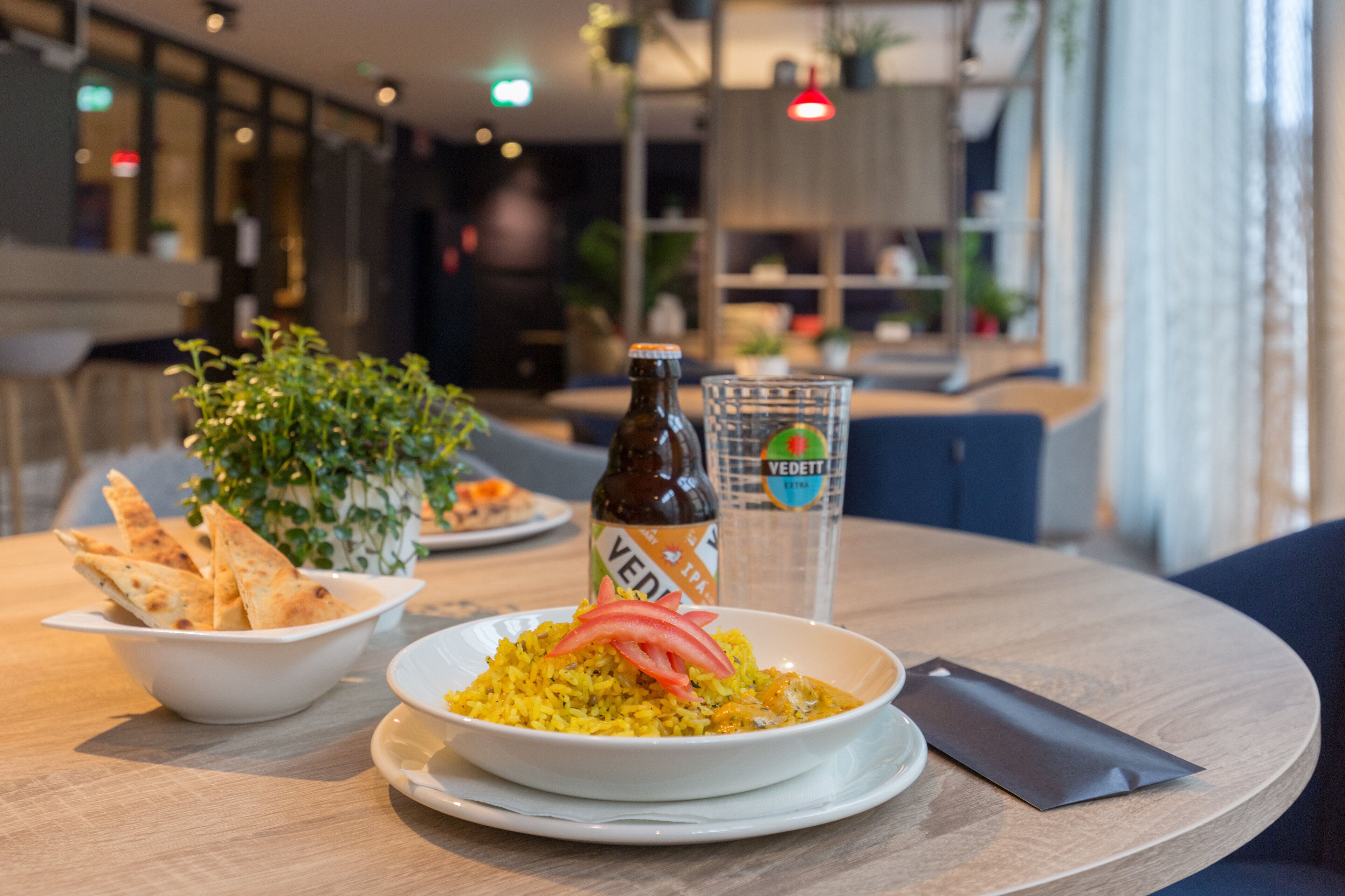 A dining table with a bowl of rice, a bottle of beer, and a glass of beer.