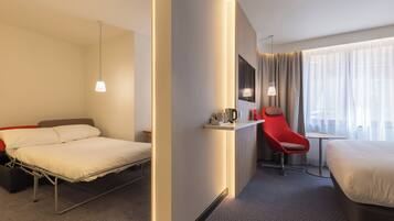 Habitación de hotel con cama, escritorio, silla y ventana con cortinas.