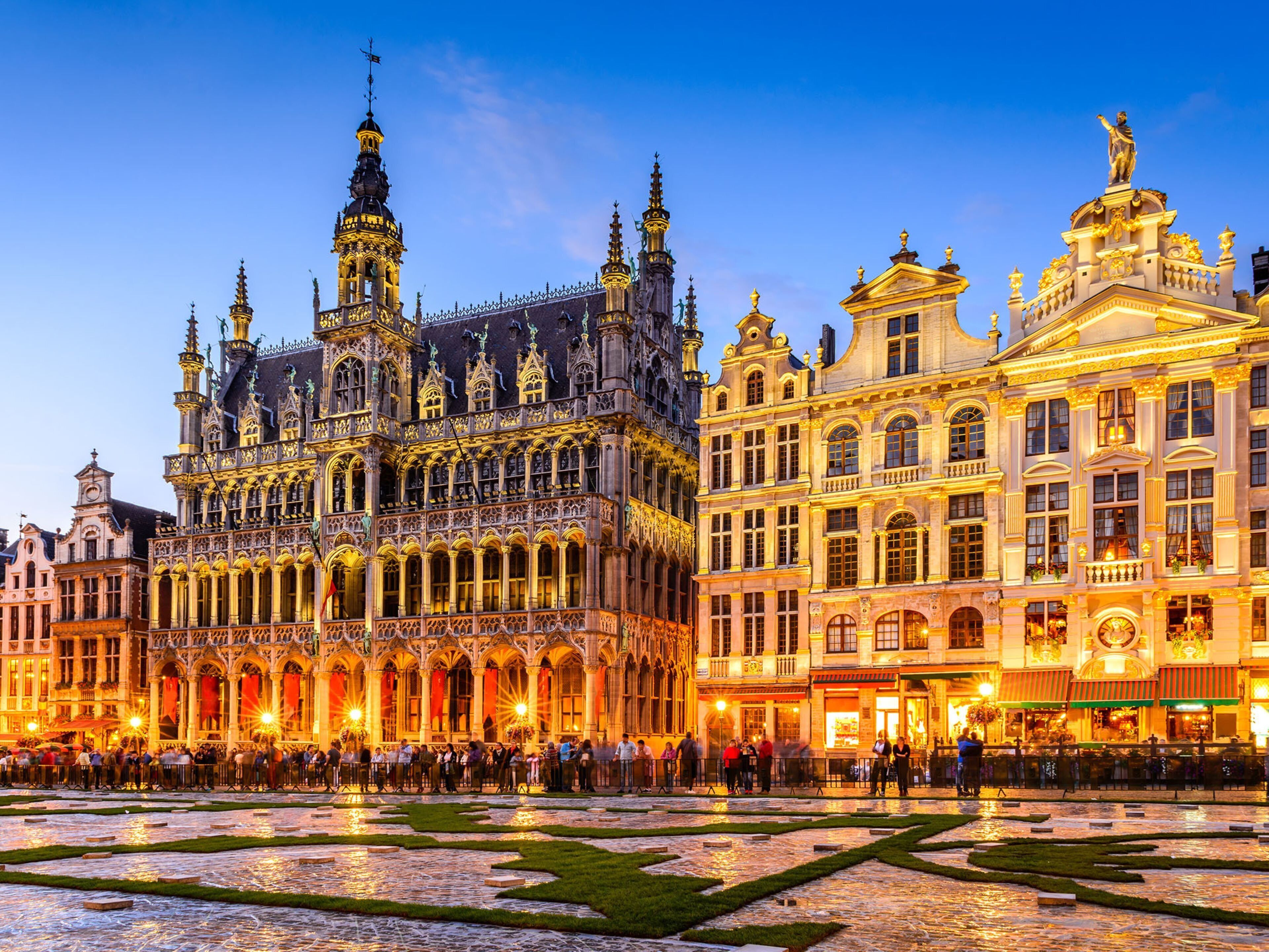 A historic building with ornate architecture, a courtyard, and a group of people gathered in front.
