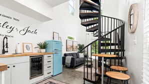 A modern kitchen with a blue refrigerator, a black spiral staircase, and a living area with a gray sofa and a blue accent wall. -  THE JACK 3 (Waco)
