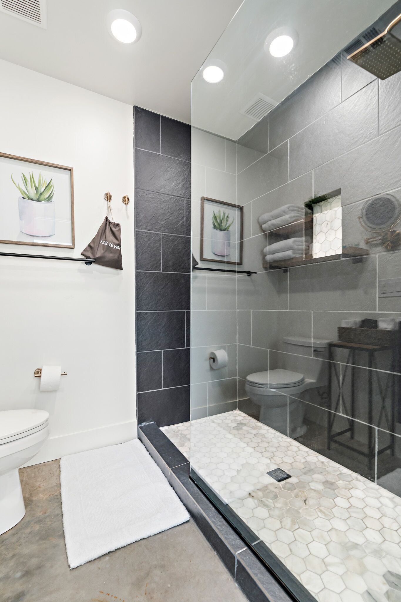 A modern bathroom with a glass-enclosed shower, a toilet, and a sink.